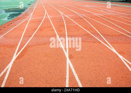 La pista rossa brillante di un'università di Wuhan. La curva bianca si interseca con la linea retta. Foto Stock