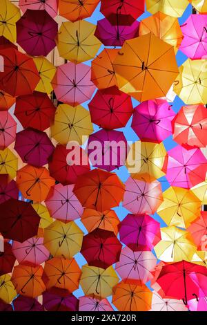 Ombrelli colorati sospesi su una strada in uno spazio aperto Foto Stock