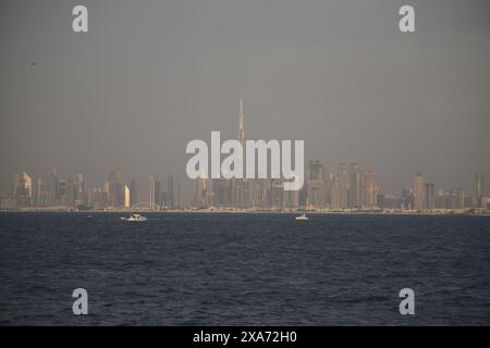 Barche a vela vicino allo skyline di Dubai con edifici sullo sfondo Foto Stock