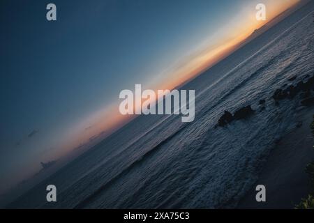 Tramonto panoramico sull'orizzonte dell'oceano dalla spiaggia Foto Stock