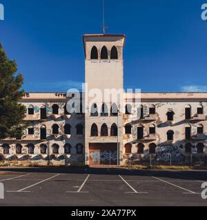 Edificio urbano bianco abbandonato con pareti coperte di graffiti sotto cieli limpidi Foto Stock