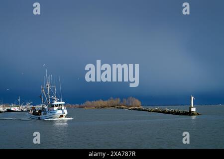 Richmond, Canada – 7 marzo 2020. Sciabola da pesca Steveston Harbor Black Clouds. Una barca con sciabica esce dall'ingresso del porto di Steveston. Foto Stock