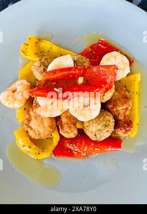 Un piatto di gamberetti, peperoni cotti e polpette su un piatto oleoso Foto Stock