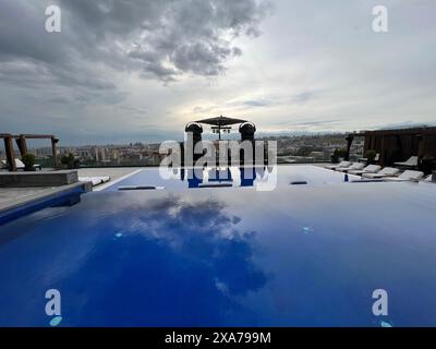 Una piscina all'aperto con lettini e ombrelloni, che offre una vista sulla città Foto Stock