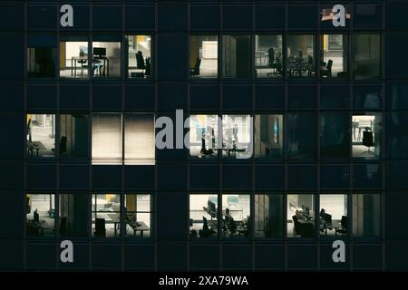 Guardando negli uffici vuoti illuminati nel grattacielo di notte Foto Stock