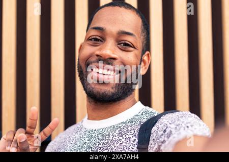 Un uomo che fa un segno di pace con le mani alzate Foto Stock