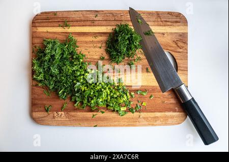 Le erbe appena tritate su un tagliere di legno con un coltello dello chef. Foto Stock