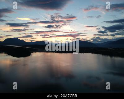 Tramonto che si riflette nell'acqua con colline sullo sfondo e luce che splende dalla superficie Foto Stock