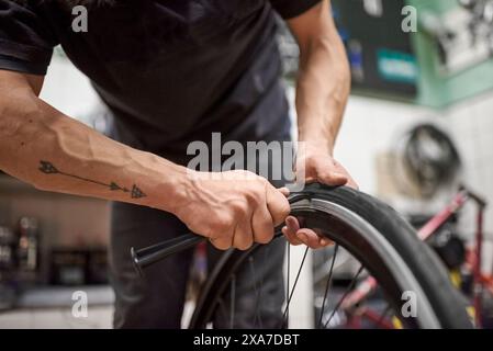 Non si conosce il riparatore di biciclette che installa uno pneumatico in gomma piena senza aria su una ruota da bici in un'officina di riparazione. Composizione selettiva della messa a fuoco con spazio di copia. Foto Stock