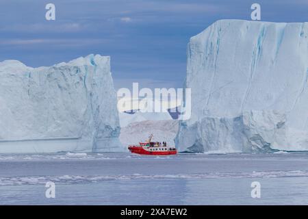 Barca turistica di fronte agli iceberg, al fiordo ghiacciato di Kangia, alla baia di Disko, sito Patrimonio dell'Umanità dell'UNESCO, alla Groenlandia occidentale e alla Groenlandia Foto Stock