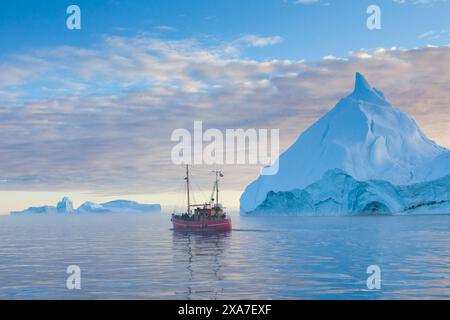 Barca turistica di fronte agli iceberg, al fiordo ghiacciato di Kangia, alla baia di Disko, sito Patrimonio dell'Umanità dell'UNESCO, alla Groenlandia occidentale e alla Groenlandia Foto Stock