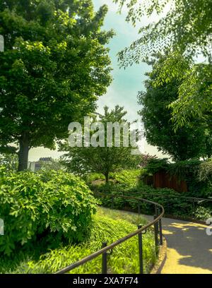 Porta d'ingresso in ferro al lussureggiante parco con alberi e cespugli Foto Stock