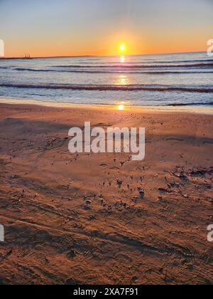 Spiaggia sabbiosa al tramonto con impronte nella sabbia Foto Stock