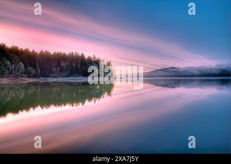 Un'acqua tranquilla riflette un cielo rosa al tramonto Foto Stock