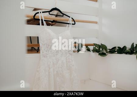 Elegante abito da sposa in pizzo appeso sul portapacchi del corridoio Foto Stock