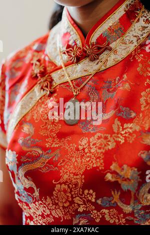 Primo piano di una donna con una camicia rossa asiatica e gioielli coordinati Foto Stock
