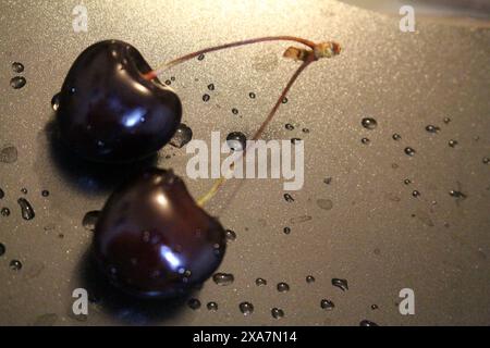 Le ciliegie fresche con goccioline d'acqua su fondo argentato Foto Stock