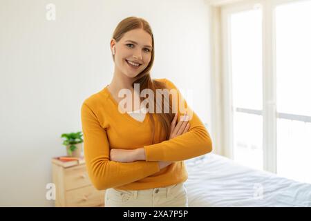 Ragazza in piedi in camera da letto con le braccia incrociate Foto Stock