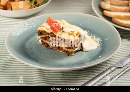 Un pezzo di gustose lasagne calde servite su un piatto blu. Cucina italiana. lasagne di carne con salsa cremosa. Foto Stock