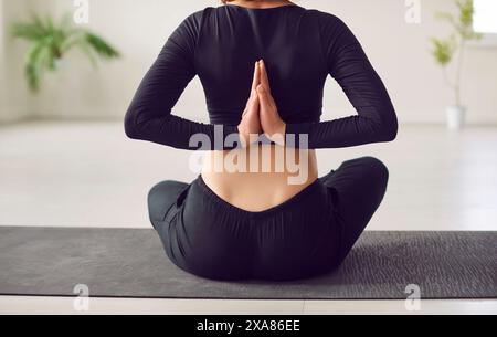 Giovane donna, vista posteriore namaste gesti, pratica yoga, seduta nell'esercizio Ardha Padmasana Foto Stock