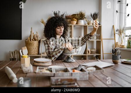 donna potter che scatta selfie in studio con strumenti in ceramica Foto Stock