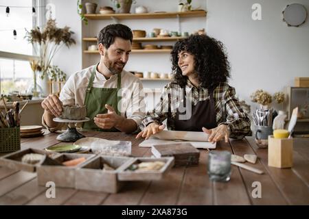 Uomo e donna maturi che scolpiscono l'argilla insieme in un laboratorio di ceramica Foto Stock
