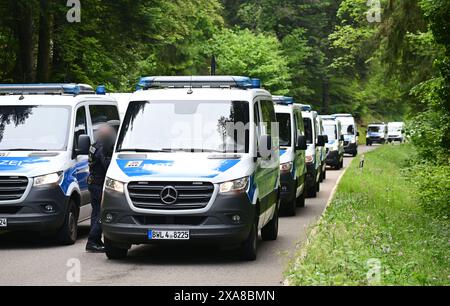 Bad Teinach Zavelstein, Germania. 5 giugno 2024. I veicoli della polizia guidano lungo una strada di fronte a un albergo in un'area boscosa. Un complesso edilizio e una proprietà sono perquisiti in connessione con un raid contro sospetti sostenitori di un gruppo Reichsbürger. Crediti: Bernd Weißbrod/dpa/Alamy Live News Foto Stock