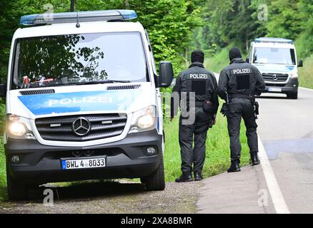 Bad Teinach Zavelstein, Germania. 5 giugno 2024. I veicoli della polizia guidano lungo una strada di fronte a un albergo in un'area boscosa. Un complesso edilizio e una proprietà sono perquisiti in connessione con un raid contro sospetti sostenitori di un gruppo Reichsbürger. Crediti: Bernd Weißbrod/dpa/Alamy Live News Foto Stock