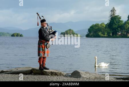 Il solitario Richard Cowie, dei massoni della Cumbria, scalda le sue pipe prima di giocare sul ponte di una delle crociere sul lago Windermere, i tradizionali piroscafi a Bowness-on-Windermere, Lake District, durante un evento commemorativo del D-Day. Il Pifferaio ha giocato in varie località della Cumbria meridionale negli ultimi 8 giorni, per onorare il pifferaio del D-Day Bill Millin che ha giocato sulle spiagge della Normandia il D-Day per confondere le truppe nemiche e aumentare il morale delle truppe alleate. Data foto: Mercoledì 5 giugno 2024. Foto Stock