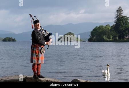 Il solitario Richard Cowie, dei massoni della Cumbria, scalda le sue pipe prima di giocare sul ponte di una delle crociere sul lago Windermere, i tradizionali piroscafi a Bowness-on-Windermere, Lake District, durante un evento commemorativo del D-Day. Il Pifferaio ha giocato in varie località della Cumbria meridionale negli ultimi 8 giorni, per onorare il pifferaio del D-Day Bill Millin che ha giocato sulle spiagge della Normandia il D-Day per confondere le truppe nemiche e aumentare il morale delle truppe alleate. Data foto: Mercoledì 5 giugno 2024. Foto Stock