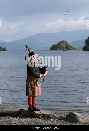 Il solitario Richard Cowie, dei massoni della Cumbria, scalda le sue pipe prima di giocare sul ponte di una delle crociere sul lago Windermere, i tradizionali piroscafi a Bowness-on-Windermere, Lake District, durante un evento commemorativo del D-Day. Il Pifferaio ha giocato in varie località della Cumbria meridionale negli ultimi 8 giorni, per onorare il pifferaio del D-Day Bill Millin che ha giocato sulle spiagge della Normandia il D-Day per confondere le truppe nemiche e aumentare il morale delle truppe alleate. Data foto: Mercoledì 5 giugno 2024. Foto Stock