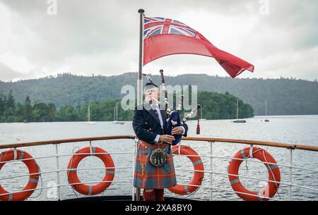 Il solitario Richard Cowie, dei massoni della Cumbria, gioca sul ponte di una delle crociere sul lago Windermere, i tradizionali piroscafi a Bowness-on-Windermere, Lake District, durante un evento commemorativo del D-Day. Il Pifferaio ha giocato in varie località della Cumbria meridionale negli ultimi 8 giorni, per onorare il pifferaio del D-Day Bill Millin che ha giocato sulle spiagge della Normandia il D-Day per confondere le truppe nemiche e aumentare il morale delle truppe alleate. Data foto: Mercoledì 5 giugno 2024. Foto Stock