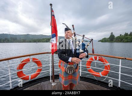 Il solitario Richard Cowie, dei massoni della Cumbria, gioca sul ponte di una delle crociere sul lago Windermere, i tradizionali piroscafi a Bowness-on-Windermere, Lake District, durante un evento commemorativo del D-Day. Il Pifferaio ha giocato in varie località della Cumbria meridionale negli ultimi 8 giorni, per onorare il pifferaio del D-Day Bill Millin che ha giocato sulle spiagge della Normandia il D-Day per confondere le truppe nemiche e aumentare il morale delle truppe alleate. Data foto: Mercoledì 5 giugno 2024. Foto Stock