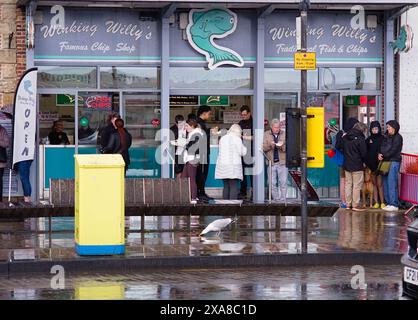 Persone che si rifugiano nel negozio di pesce e chip di Willy durante una forte doccia a Scarborough Foto Stock