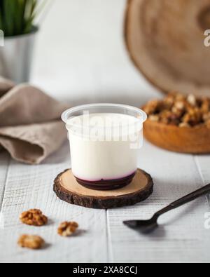 Panna cotta di ciliegio in tazza di plastica e noci in tavola Foto Stock