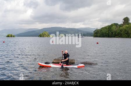 Un paddle boarder sul lago Windermere in Cumbria. Data foto: Mercoledì 5 giugno 2024. Foto Stock