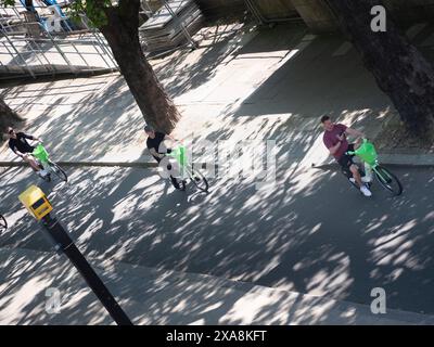 Fila di motociclisti Lime noleggiati, che percorrono l'argine nel centro di Londra, con telecamere del traffico in primo piano Foto Stock