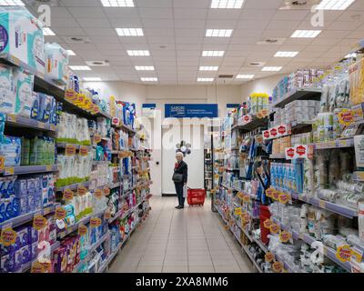 Cremona, Italia - 27 maggio 2024 negozi di donna anziana in un supermercato affollato, scegliendo tra una vasta gamma di prodotti Foto Stock