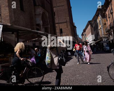 Cremona, Italia - 27 maggio 2024 turisti e gente del posto si godono una giornata di sole passeggiando per un mercato italiano. Un'alta torre di mattoni si erge sopra Foto Stock