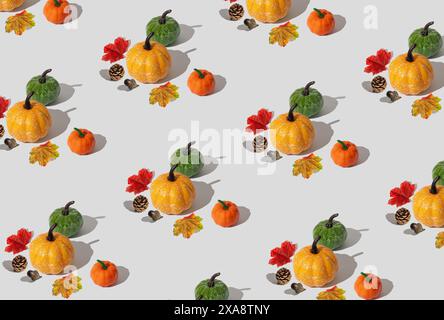 Motivo autunnale o autunnale alla moda con zucche, foglie cadute gialle e rosse, noci e pinne su sfondo bianco. Disposizione minima degli oggetti autunnali. Foto Stock
