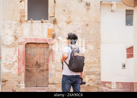 fotografo viaggiatore che guarda un'antica città con una macchina fotografica in mano Foto Stock