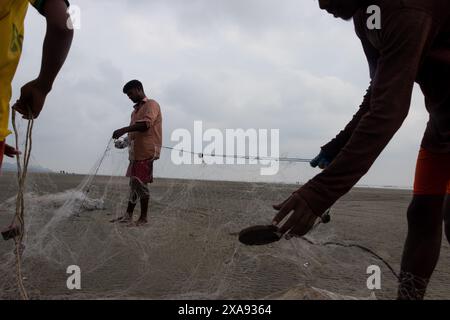 5 giugno 2024, Cox's Bazar, Chittagong, Bangladesh: Pescatori che preparano le reti da pesca per pescare il pesce sulla spiaggia di Cox's Bazar, Bangladesh. Il sostentamento della comunità dei pescatori dipende in larga misura dalla pesca. Con ogni nodo e regolazione, onorano una tradizione senza tempo di sostentamento che si armonizza con i ritmi del mondo naturale. Cox's Bazar, la spiaggia marina naturale più lunga del mondo, si estende per oltre 120 chilometri lungo la costa sud-orientale del Bangladesh. Rinomato per le sue sabbie dorate, i vivaci tramonti e il surf ondulato, attrae milioni di turisti ogni anno. (Immagine di credito: © Joy Foto Stock