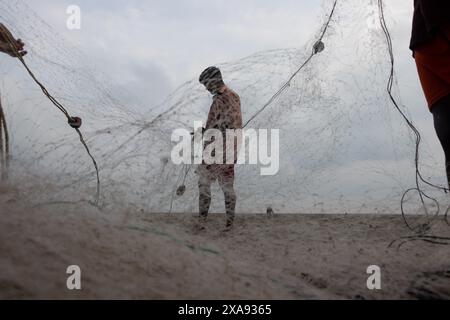 5 giugno 2024, Cox's Bazar, Chittagong, Bangladesh: Pescatori che preparano le reti da pesca per pescare il pesce sulla spiaggia di Cox's Bazar, Bangladesh. Il sostentamento della comunità dei pescatori dipende in larga misura dalla pesca. Con ogni nodo e regolazione, onorano una tradizione senza tempo di sostentamento che si armonizza con i ritmi del mondo naturale. Cox's Bazar, la spiaggia marina naturale più lunga del mondo, si estende per oltre 120 chilometri lungo la costa sud-orientale del Bangladesh. Rinomato per le sue sabbie dorate, i vivaci tramonti e il surf ondulato, attrae milioni di turisti ogni anno. (Immagine di credito: © Joy Foto Stock