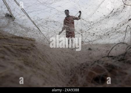 5 giugno 2024, Cox's Bazar, Chittagong, Bangladesh: Pescatori che preparano le reti da pesca per pescare il pesce sulla spiaggia di Cox's Bazar, Bangladesh. Il sostentamento della comunità dei pescatori dipende in larga misura dalla pesca. Con ogni nodo e regolazione, onorano una tradizione senza tempo di sostentamento che si armonizza con i ritmi del mondo naturale. Cox's Bazar, la spiaggia marina naturale più lunga del mondo, si estende per oltre 120 chilometri lungo la costa sud-orientale del Bangladesh. Rinomato per le sue sabbie dorate, i vivaci tramonti e il surf ondulato, attrae milioni di turisti ogni anno. (Immagine di credito: © Joy Foto Stock