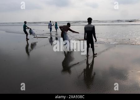 5 giugno 2024, Cox's Bazar, Chittagong, Bangladesh: Pescatori che preparano le reti da pesca per pescare il pesce sulla spiaggia di Cox's Bazar, Bangladesh. Il sostentamento della comunità dei pescatori dipende in larga misura dalla pesca. Con ogni nodo e regolazione, onorano una tradizione senza tempo di sostentamento che si armonizza con i ritmi del mondo naturale. Cox's Bazar, la spiaggia marina naturale più lunga del mondo, si estende per oltre 120 chilometri lungo la costa sud-orientale del Bangladesh. Rinomato per le sue sabbie dorate, i vivaci tramonti e il surf ondulato, attrae milioni di turisti ogni anno. (Immagine di credito: © Joy Foto Stock