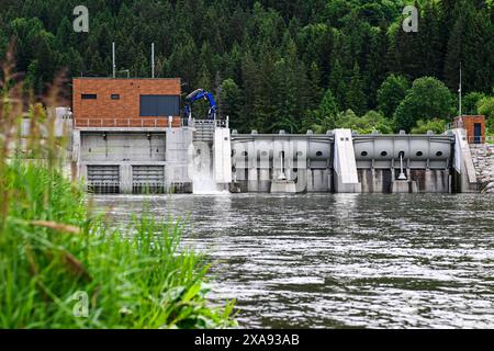 Una piccola diga idroelettrica opera in una zona boschiva, esemplificando la produzione di energia sostenibile. Foto Stock