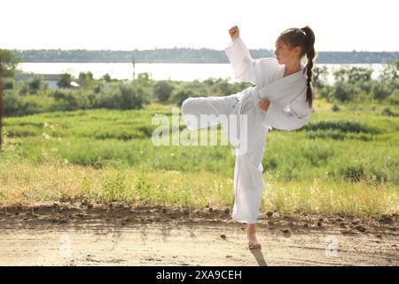 Carina bambina in kimono pratica karate all'aperto Foto Stock