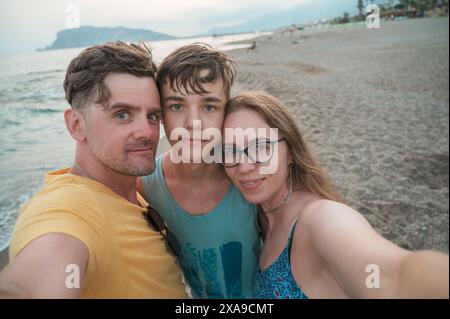 Famiglia felice che scatta una foto su una spiaggia al mare nella città di Alanya, Turchia. Concetto di viaggio o vacanza Foto Stock