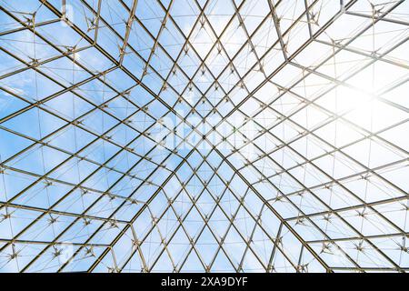 Sotto la Piramide del Louvre, l'intricata lavorazione del vetro contrasta con un cielo blu in una giornata limpida a Parigi, in Francia Foto Stock