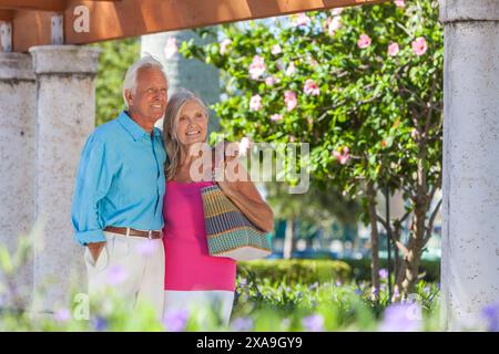 Un anziano felice e una vecchia coppia che camminano insieme fuori sotto il sole Foto Stock